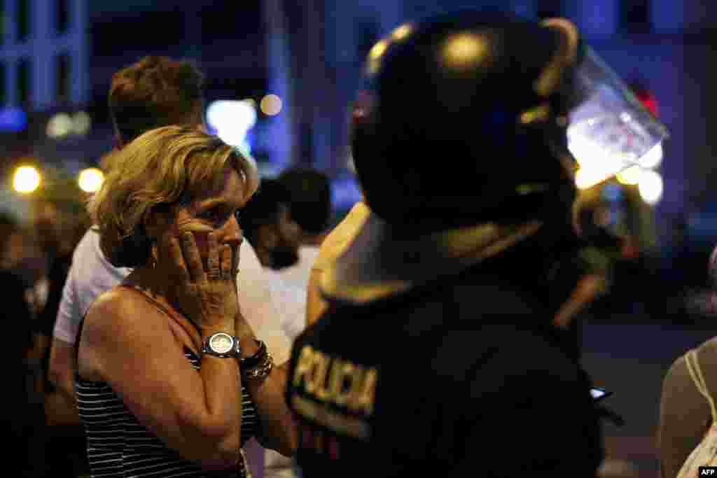 Una mujer es escoltada por la policía en España para sacarla de una zona acordonada luego de que una van embistiera a peatones en Las Ramblas, Barcelona. 