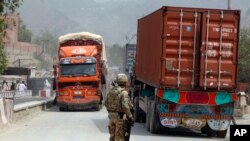 FILE - U.S. soldier watches trucks crossing Torkham gate border between Afghanistan and Pakistan in Nangarhar province, Afghanistan.