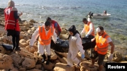 Des secouristes portent un sac où un corps d'un migrant est allongé, près de Tripoli, en Libye, le 5 novembre 2016. 