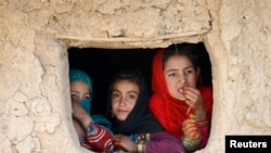 Des jeunes filles afghanes regardent par la fenêtre d'un camp de déplacés à Kaboul, le 14 octobre 2014. 