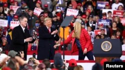 U.S. President Donald Trump applauds as he hosts a campaign event with U.S. Republican Senators David Perdue (L) and Kelly Loeffler (R) at Valdosta Regional Airport in Valdosta, Georgia, U.S., December 5, 2020.