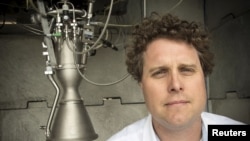 FILE - Rocket Lab CEO Peter Beck poses alongside a Rutherford rocket engine in Auckland, New Zealand, Oct. 20, 2015. 