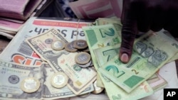 FILE - A man counts Zimbabwean dollar notes and coins next to a ten US dollar note on the streets of Harare, June 25, 2019. 