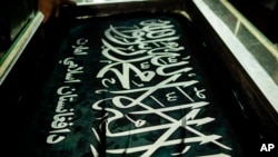 FILE - A worker hand prints Taliban flags in a small workshop in Kabul's Jawid market, Afghanistan, Sept. 12, 2021. 