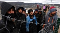 Migrants watch Bosnian soldiers put up tents at the Lipa camp outside Bihac, Bosnia, Jan. 1, 2021. Hundreds of migrants have been stuck in a burned-out camp in the northwest of the country in winter weather and with no facilities.