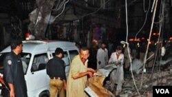 Warga Pakistan berusaha mencari para korban di lokasi serangan bom kembar di kota Peshawar (11/6).