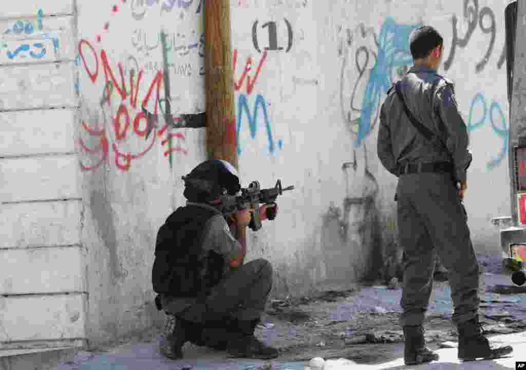 An Israeli soldier aims his gun at Palestinian protesters during clashes in Hawara village near the West Bank city of Nablus, July 25, 2014. 