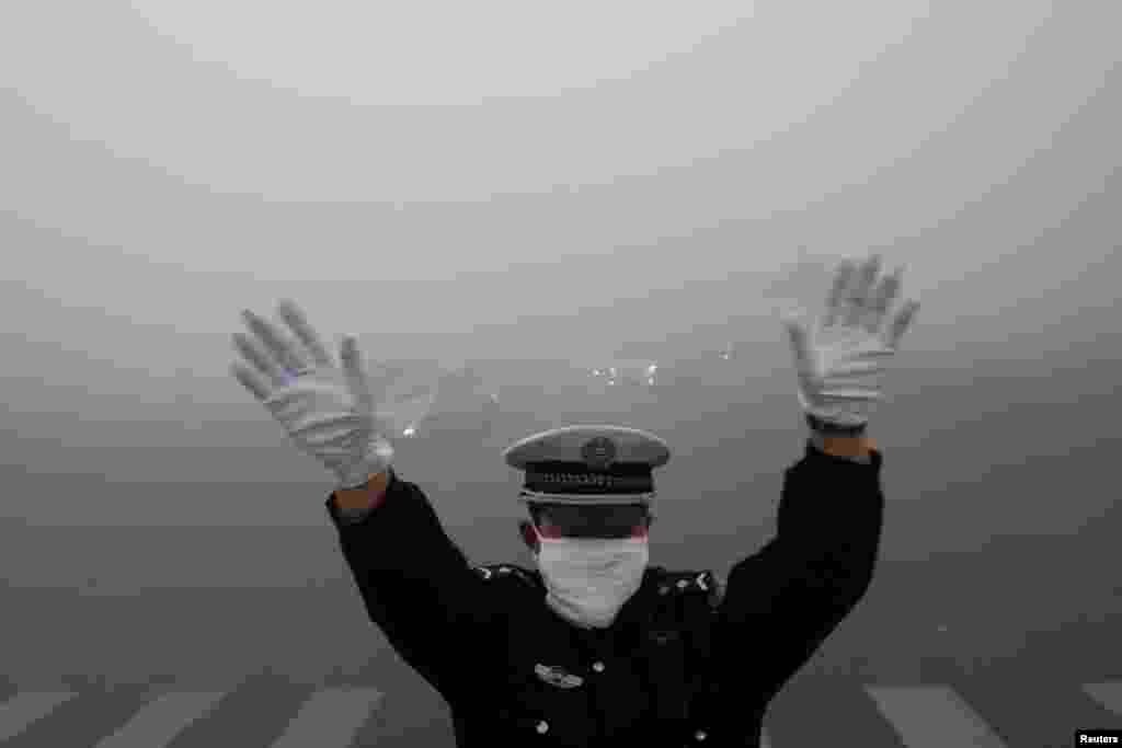 A traffic police officer signals to drivers during a smoggy day in Harbin, China, Oct. 21, 2013.