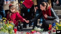 Une femmes t une petite fille allument des bougies en mémoire des victimes, Place de la Bourse, Bruxelles, 26 mars 2016.