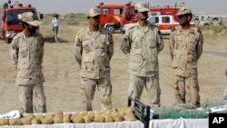 FILE - Iranian police officers stand behind narcotics that were seized at the Milak border in southeastern Iran, Oct. 10, 2012.