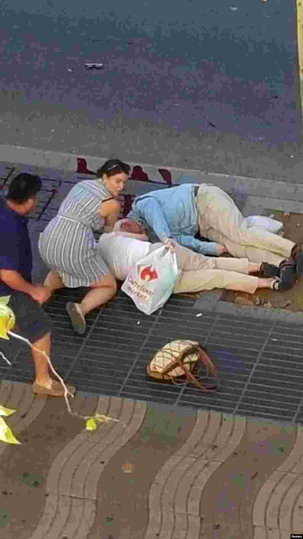 Personas atienden a heridos en el lugar donde una van embistió a peatones cerca de la avenina de Las Ramblas, en el centro de Barcelona, España.