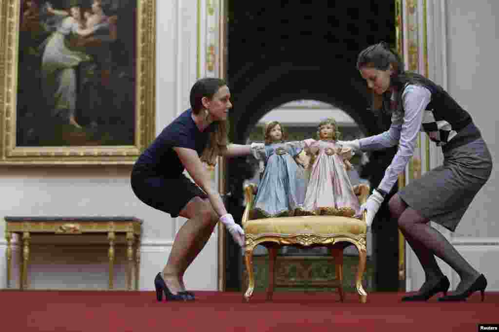 Exhibition curator Anna Reynolds (L) poses with a pair of Parisian dolls belonging to Britain's Queen Elizabeth (left doll) and her sister Princess Margaret, at Buckingham Palace in London. Toys and childhood outfits belonging to the royal family will form part of an exhibition "Royal Childhood" during the summer opening of Buckingham Palace from Jul. 26 - Sept. 28, 2014.