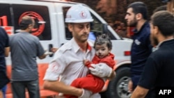 A Palestinian paramedic carries a child injured in an Israeli air strike at the Nasser hospital in Khan Yunis in the southern of Gaza Strip, on Oct. 17, 2023.