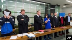 Trois des six jeunes hommes accusés d'une tentative de meurtre se couvrent le visage au cours d’une audience lors de leur procès au tribunal régional de Berlin, Allemagne, 13 juin 2017. 