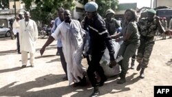 Des éléments des forces de sécurité transportent dans transportent dans une couverture le reste du corps d'un homme déchiqueté par une double explosion à Maroua, dans le Nord du Cameroun, le 22 juillet 2015