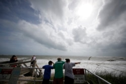 People on a boardwalk look out over the high surf from the Atlantic Ocean, in advance of the potential arrival of Hurricane Dorian, in Vero Beach, Florida, Sept. 2, 2019.