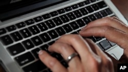 FILE - A person works on a laptop on June 19, 2017, in North Andover, Massachusetts. (AP Photo/Elise Amendola, File)