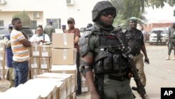 Afisa wa polisi akilinda doria wakati wafanyakazi wa tume ya uchaguzi Nigeria wakipakia vifaa vya kupiga kura katika malori ili kuvipeleka katika vituo vya kupiga kura huko Yola, Nigeria, Feb. 15, 2019.