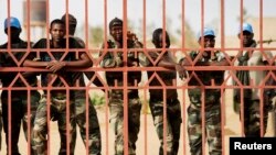FILE - U. N. peacekeepers peer from behind a gate in Gao during a protest against sending them to the northern rebel-held town of Kidal, Mali, where attempts to reach an accord between the government and rebel movements have proven difficult.
