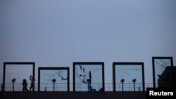 A tourist looks toward the north through a binoculars as another takes pictures at Imjingak Pavilion near the demilitarized zone (DMZ), which separates the two Koreas, in Paju, north of Seoul, March 14, 2013. 