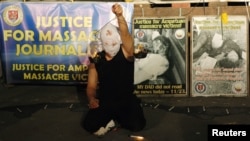 A masked Filipino artist holds up a replica of a burning weighing scale signifying justice to commemorate the 2nd year anniversary of the "Maguindanao Massacre" at the National Press Club compound in Manila, November 23, 2011.