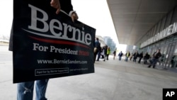 Seorang pendukung Bernie Sanders, kandidat capres dari Partai Demokrat memegang poster di luar Huntington Convention Center, di Cleveland, 10 Maret 2020. (Foto: AP)