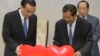 China's Premier Li Keqiang, left, pulls a symbol of China-Cambodia Heart Journey, together with his Cambodian counterpart Hun Sen, center, during a signing ceremony at Peace Palace in Phnom Penh, Cambodia, Thursday, Jan. 11, 2018. Cambodia and China on Thursday signed nearly 20 agreements worth several billion dollars to develop the impoverished Southeast Asian country's infrastructure, agriculture and healthcare. (AP Photo/Heng Sinith)
