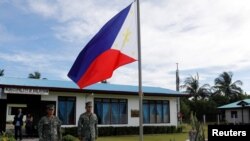 ARSIP - Serdadu-serdadu Filipina bersiaga di samping bendera Filipina di pulau Thitu, sebuah pulau yang dipersengketakan di Laut China Selatan, 21 April 2017 (foto: Reuters/Erik de Castro)