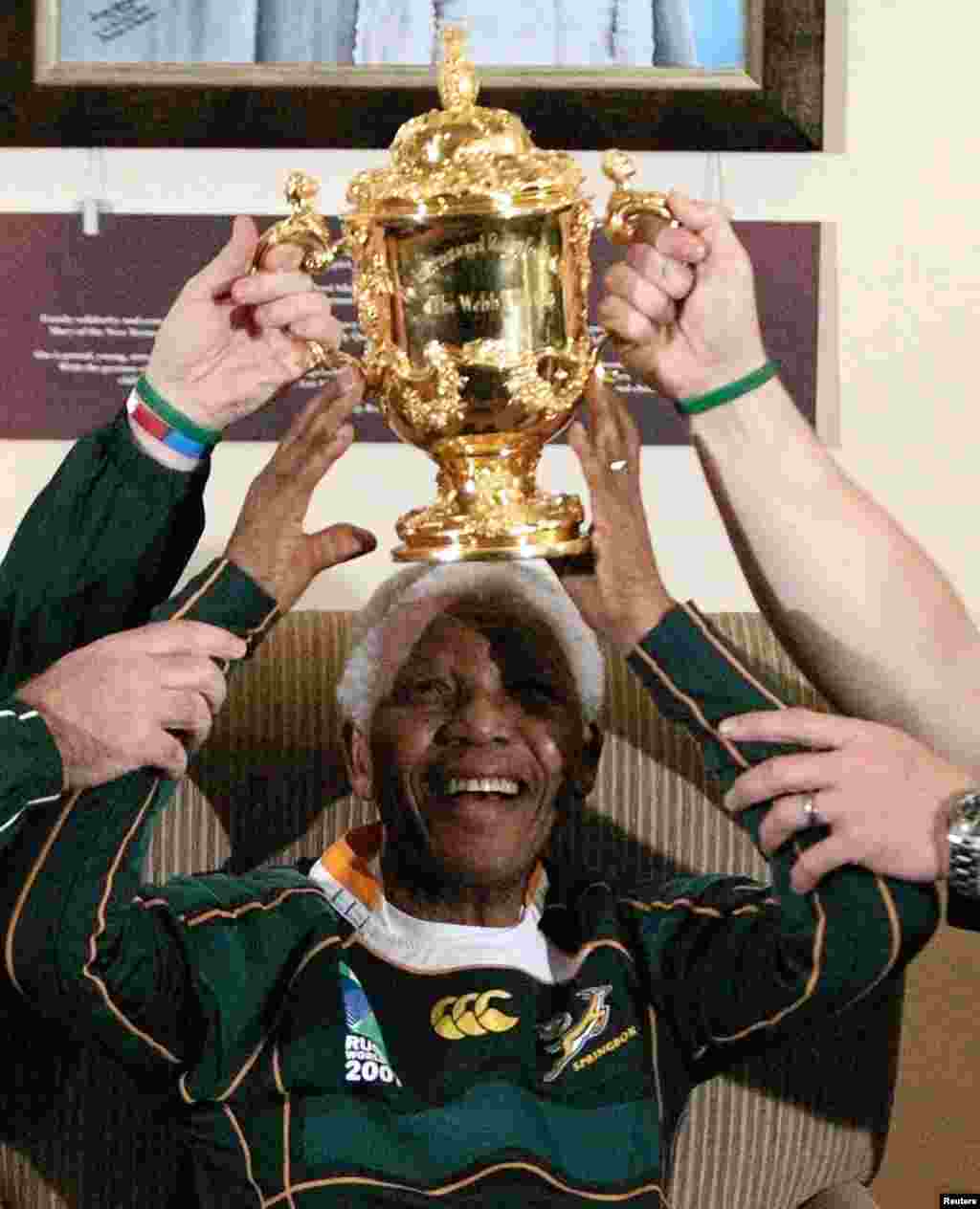 L'ancien président sud-africain Nelson Mandela souriant et aidé, soulève le trophée Webb Ellis qui lui a été présenté par les Springboks à la Fondation Mandela à Houghton Octobre 27, 2007.