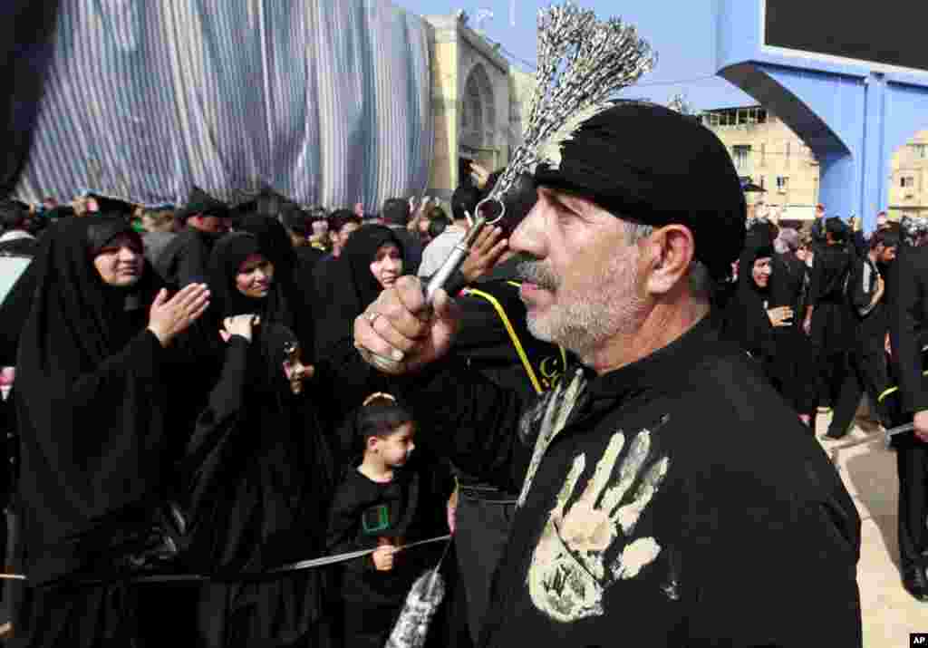 Seorang Muslim Syiah memukuli dirinya dengan rantai sebagai tanda berduka bagi Imam Hussein di antara makam Imam Hussein dan Imam Abbas di Karbala, Irak (13/11). (AP/Hadi Mizban)