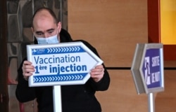FILE - An employee at the Dunkirk Hospital Center sets up signs to guide patients arriving for the COVID-19 vaccine, in Dunkirk, France, Feb. 17, 2021.