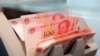 Des billets chinois de 100 yuans dans une machine de comptage de la une succursale d'une banque commerciale à Pékin, en Chine, le 30 mars 2016. 