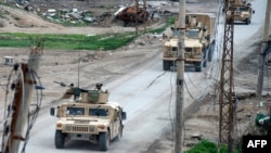 Iring-iringan kendaraan koalisi yang dipimpin AS melintasi jalanan di desa garis depan Suriah, Baghouz, 17 Februari 2019 (foto: Fadel/SENNA/AFP)