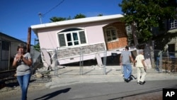 Residents survey damage where a home partially collapsed after an earthquake hit Guanica, Puerto Rico, Jan. 6, 2020.