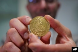 Vicken Yegparian, vice president of numismatics, Stack's Bowers Galleries, holds a golden coin once belonging to the collection of Danish king, Frederik VII, now part of L. E. Bruun's collection, in Zealand, Denmark, May 7, 2024. (AP Photo/James Brooks)