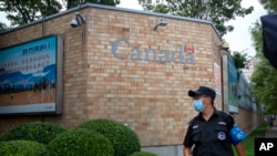 Seorang petugas keamanan mengenakan masker wajah ketika berjaga di depan kantor kedutaan besar Kanada di Beijing, pada 6 Agustus 2020. (Foto: AP/Mark Schiefelbein)