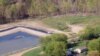 June Chappel’s home in Washington, Pennsylvania, is surrounded by gas drilling: a waste containment pond behind her and gas tanks to the side.