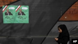 Seorang pejalan kaki berjalan melewati poster kampanye salah satu kandidat pemilihan parlemen Iran, Majid Hajifaraji di jalan Enqelab-e-Eslami, pusat kota Teheran, Iran, Kamis, 13 Februari 2020. 