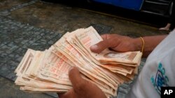 Un hombre cuenta billetes de bolívares venezolanos en una parada de autobús en Caracas. Agosto 5, 2021.