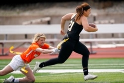 Ottawa quarterback Madysen Carrera (21) is tackled by Midland defender Casey Thompson, left, during an NAIA flag football game in Ottawa, Kan., March 26, 2021.