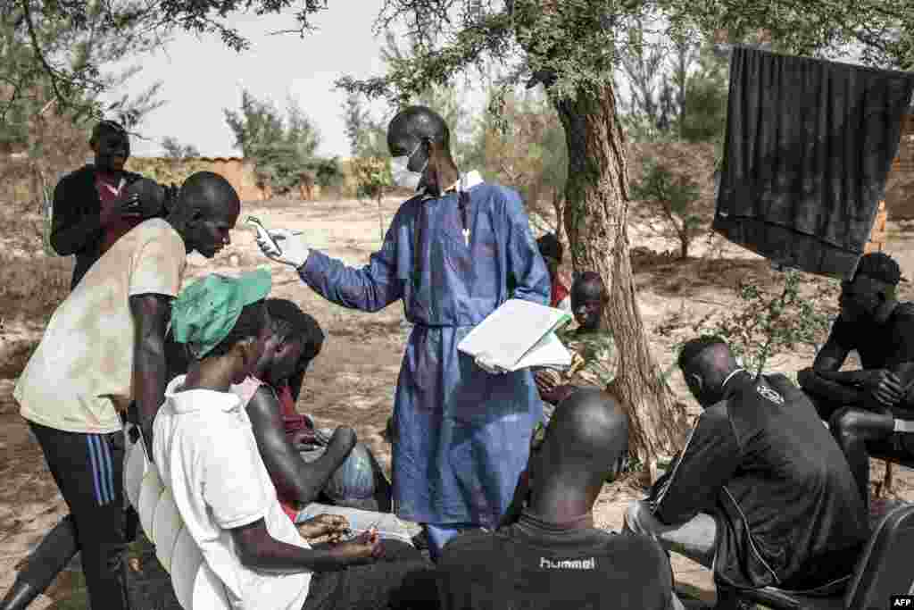 Les enfants de rue se font prendre leur température en zone de quarantaine, dans un refuge pour enfants de rue nouvellement arrivés à l'extérieur de Dakar, le 10 avril 2020.