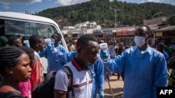 Un personnel du Rwanda Biomedical Center contrôle les passagers d'une gare routière après que le gouvernement a suspendu tous les mouvements inutiles pendant deux semaines pour freiner la propagation du coronavirus à Kigali, au Rwanda, le 22 mars 2020. (Ph.Simon Wohlfar/AFP)