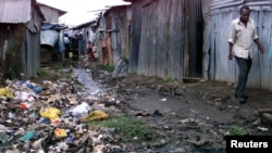 Mkazi mmoja mwa maeneo ya mabanda Kenya akitembea kuepuka uchafu katika maeneo ya ,mabanda ya Kibera nje kidogo ya jiji la Nairobi Juni 28,2002.