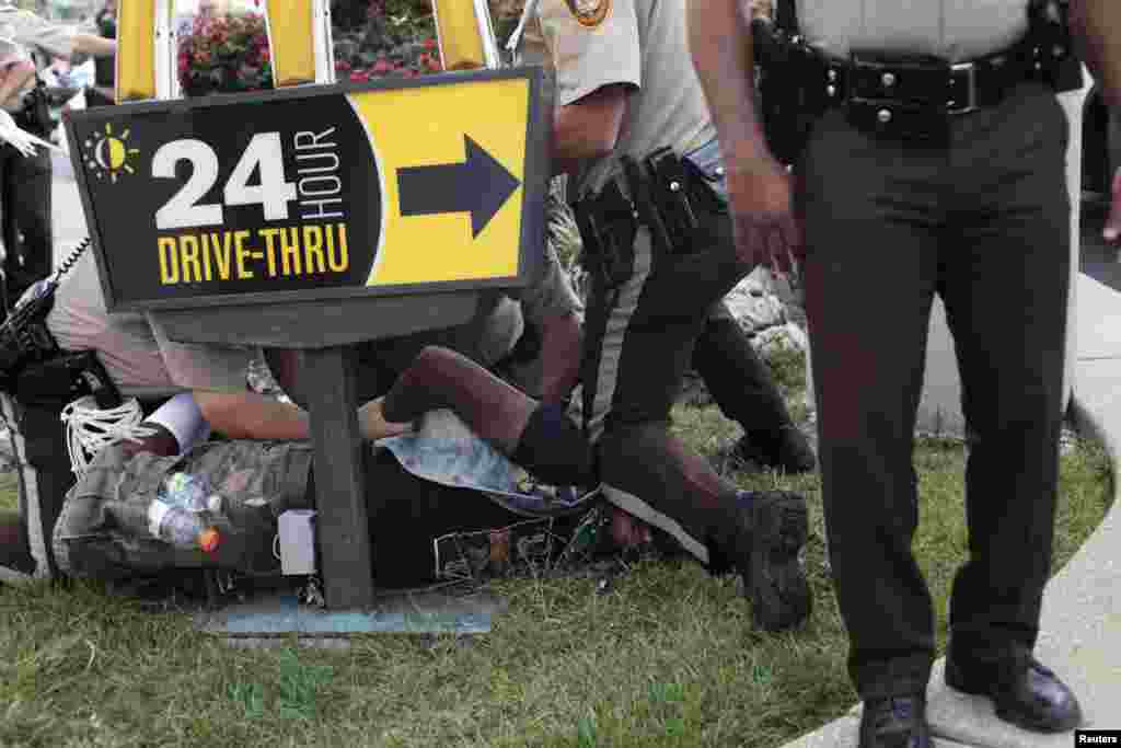 Police officers detain a demonstrator during the protest of Michael Brown's shooting death in Ferguson, Missouri, Aug. 18, 2014.