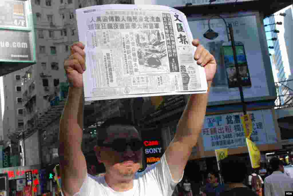 香港政治漫畫家梁阿平高舉報道1989年6月4日晚上屠城的香港《文匯報》頭版
