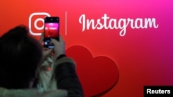 Seorang pengunjung memotret logo aplikasi Instagram di Paris, Perancis, 7 Februari 2018. 