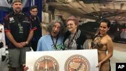Esta foto del 29/5/18 muestra al actor Peter Mayhew, al frente, a la izquierda, y a su esposa Angie, posando con la fan venezolana de Star Wars Elisa Arguello, vestida de Princesa Leia, en el 'Chewbacca Challenge'. (Elisa Arguello via AP).
