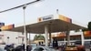 A woman walks past cars buying fuel at a gas station in Lagos, Nigeria, April 24, 2012.
