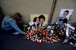 FILE - A woman kneels by a memorial on the first anniversary of the killings of the investigative reporter Jan Kuciak and his fiancee, Martina Kusnirova, in Bratislava, Slovakia, Feb. 21, 2019.