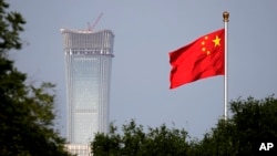 A Chinese national flag at Tiananmen Square flutters against the capital city tallest skyscraper China Zun Tower under construction at the Central Business District in Beijing Thursday, June 14, 2018.